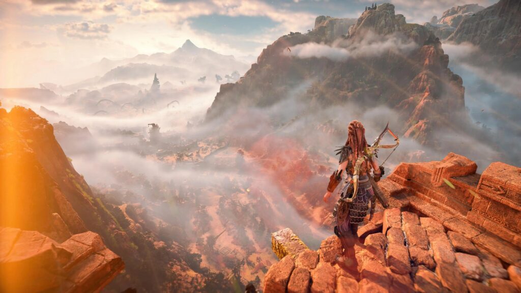 Aloy overlooking the Forbidden West from atop a tall cliff